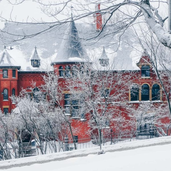 Une maison rouge est recouverte de neige et d'arbres.