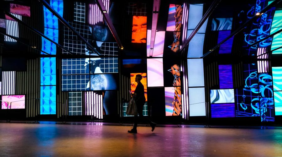 A woman walks through a room with many colorful screens during a Walking Tour.