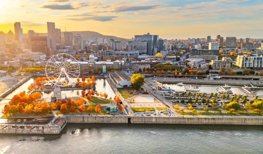 Aerial view of Old Montréal and the Grande Roue surrounded by vibrant fall foliage along the Bonsecours Basin at sunset