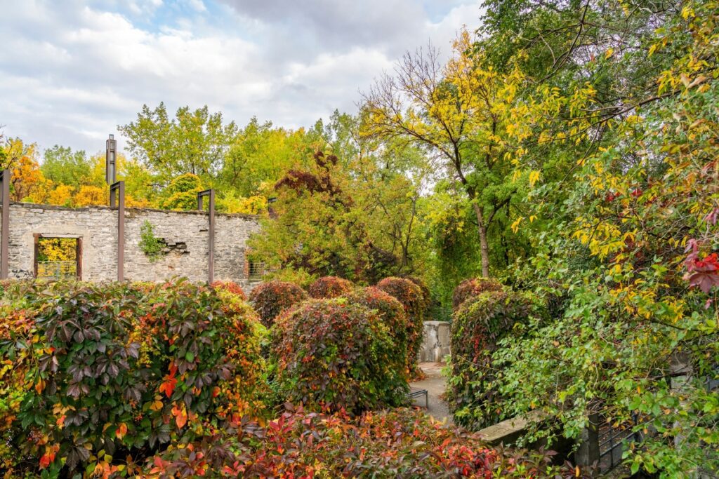 Autumn foliage surrounds the historic stone ruins and walking paths of Parc-nature de l’Île-de-la-Visitation in Montréal, with vibrant red and golden leaves adding seasonal colour.