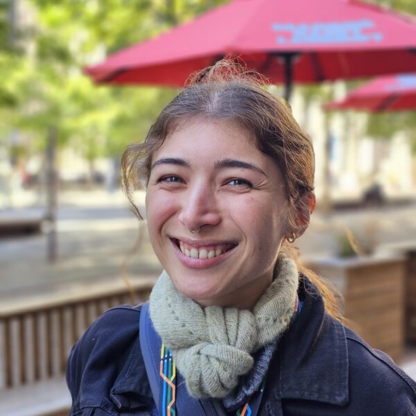 Une femme debout devant une terrasse et un immeuble lors d'une visite guidée à pied à Montréal.