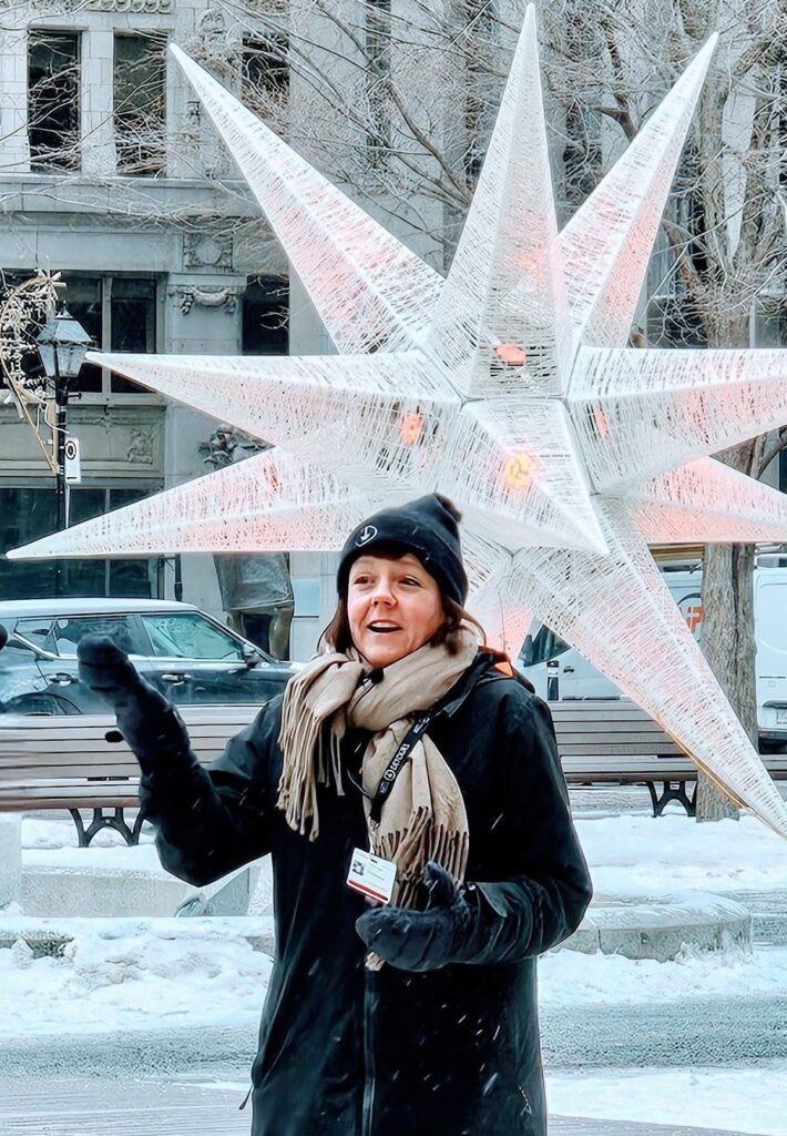 A certified Montreal tour guide wearing an official City of Montreal permit while leading a winter walking tour in front of a public art installation.