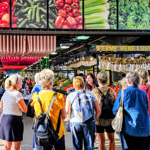 MTL Detours guide speaking with a small walking tour group inside Jean-Talon Market in Montréal.